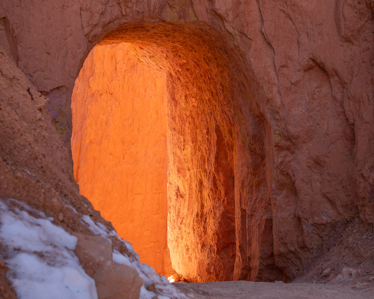 An arched doorway cut out of the rock for passage catches the light